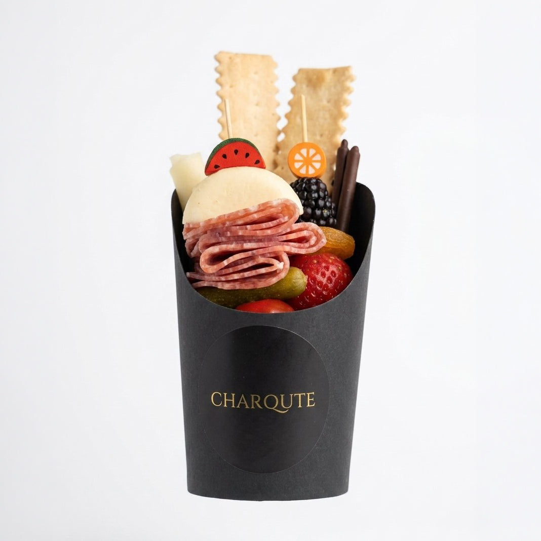 Individual charcuterie cup with premium meats, cheeses, and seasonal accompaniments by Charqute