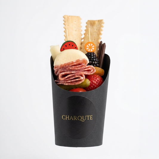 Individual charcuterie cup with premium meats, cheeses, and seasonal accompaniments by Charqute